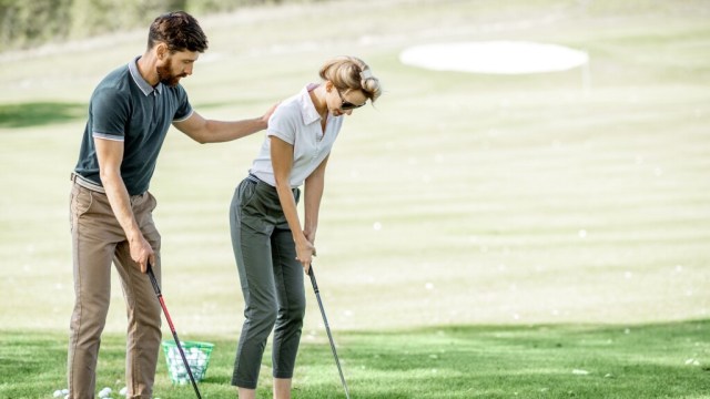 Golf instructor teaching lesson to golfer on golf course